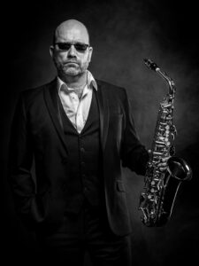 Stoere portretfoto man fotoshoot zwartwit studio saxofoon