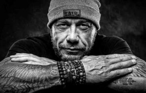 Stoere portretfoto van een man met muts en armbanden. De foto is gemaakt in de studio en in zwartwit. portretfotograaf Ed van der Weijden.