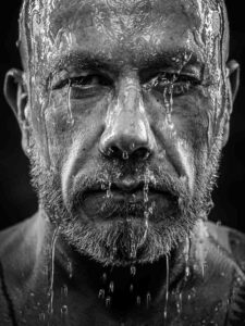 Stoere zwartwit closup portretfoto van een man met stromend water over zijn gezicht gemaakt door portretfotograaf Ed van der Weijden.